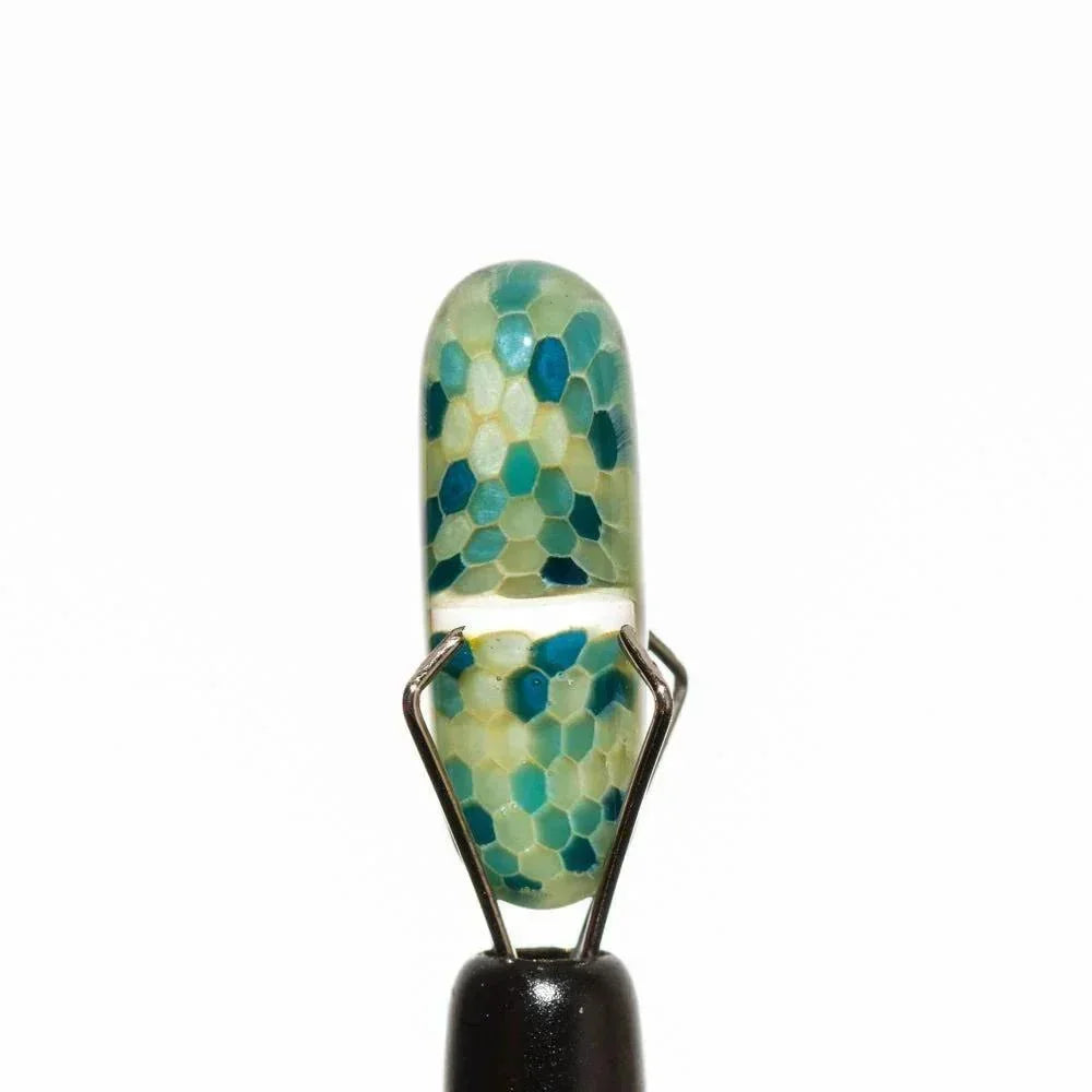 Hand-blown glass pipe with blue-green honeycomb pattern, held in metal stand