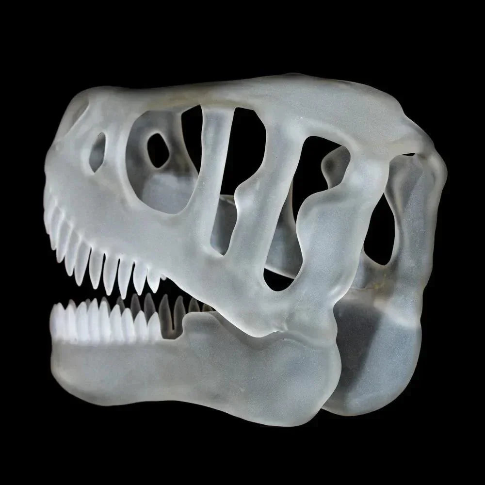 Frosted glass T-Rex skull sculpture with detailed teeth on a black background