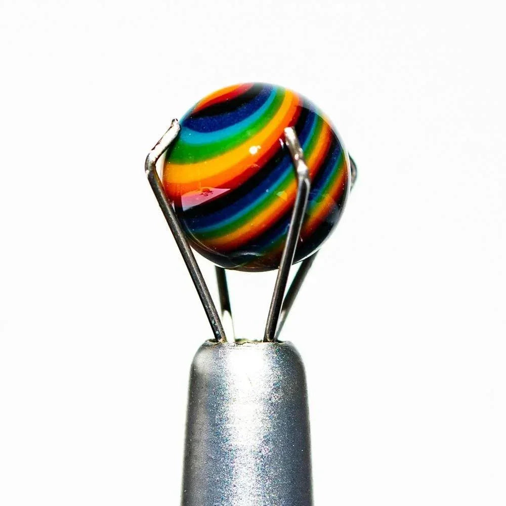 Handcrafted glass marble with vibrant rainbow stripes held by metal prongs