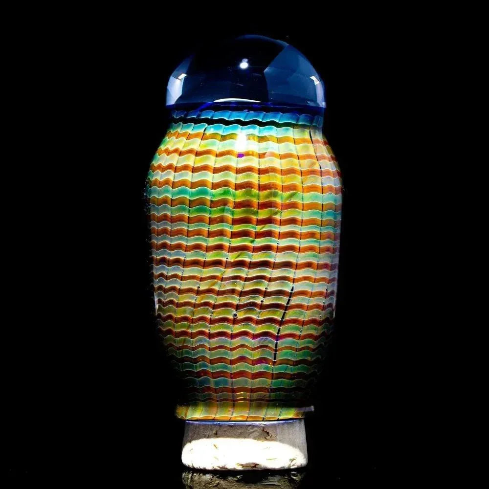 Colorful wavy glass jar with blue dome lid, artistic heady glass accessory on black background.
