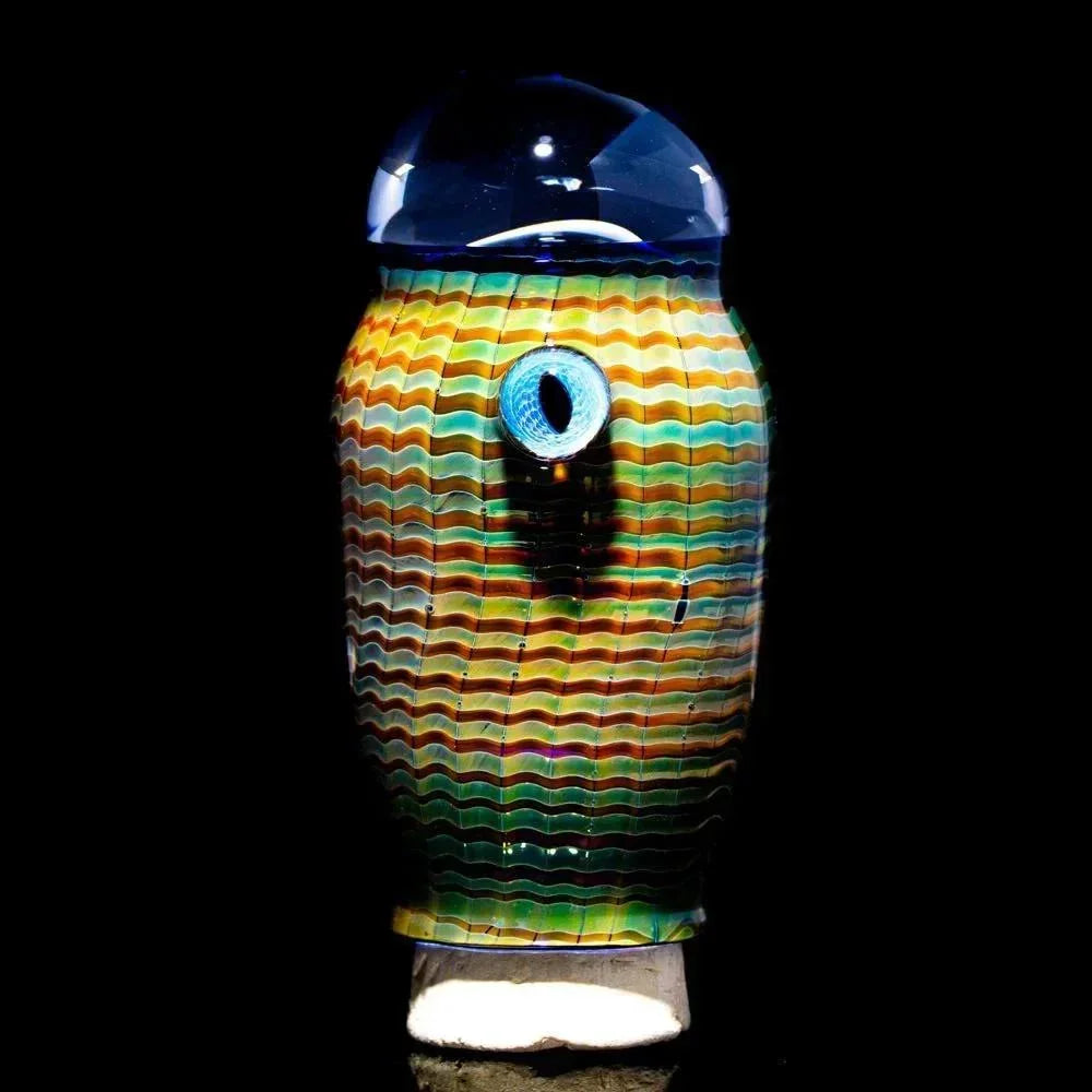 Colorful glass jar with wavy stripes and a decorative blue eye accent on a black background.