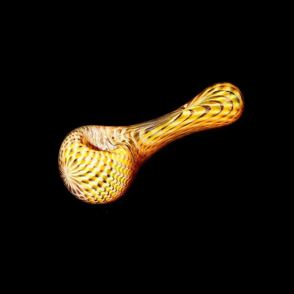 Yellow glass hand pipe with intricate retti pattern on black background