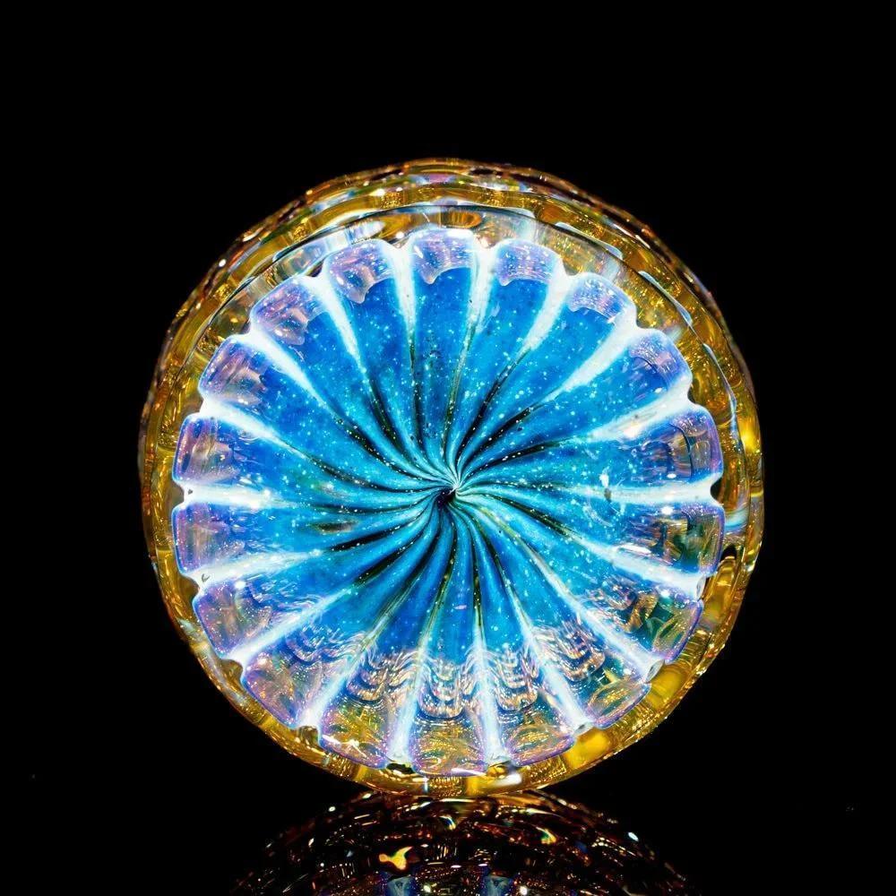Colorful artisan glass jar with swirling blue and gold patterns, displayed on black background.