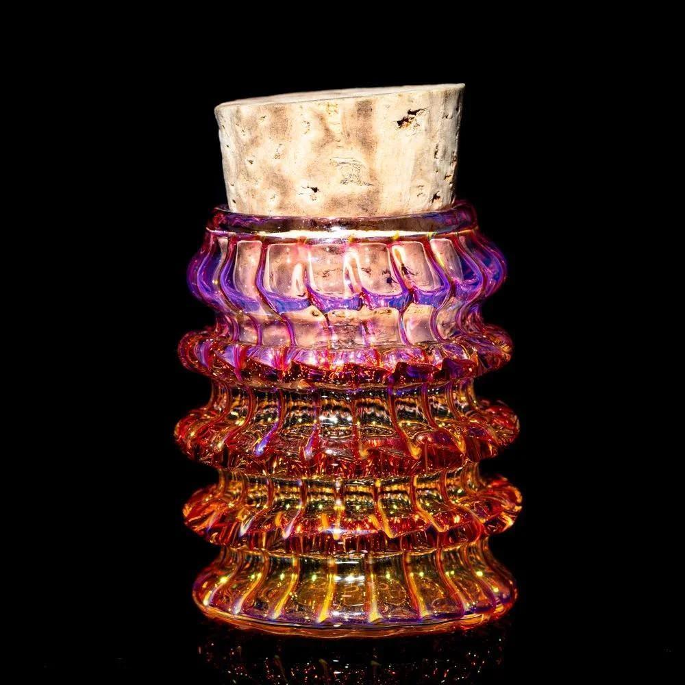 Colorful textured glass jar with cork lid, artisan glass storage container on black background