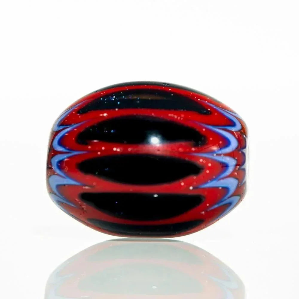 Handmade glass bead with red and black chevron marquise design on a white background