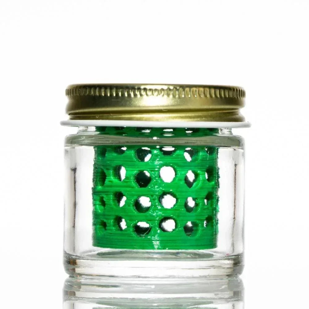 Clear glass jar with gold lid, featuring a green perforated insert for accessory cleaning