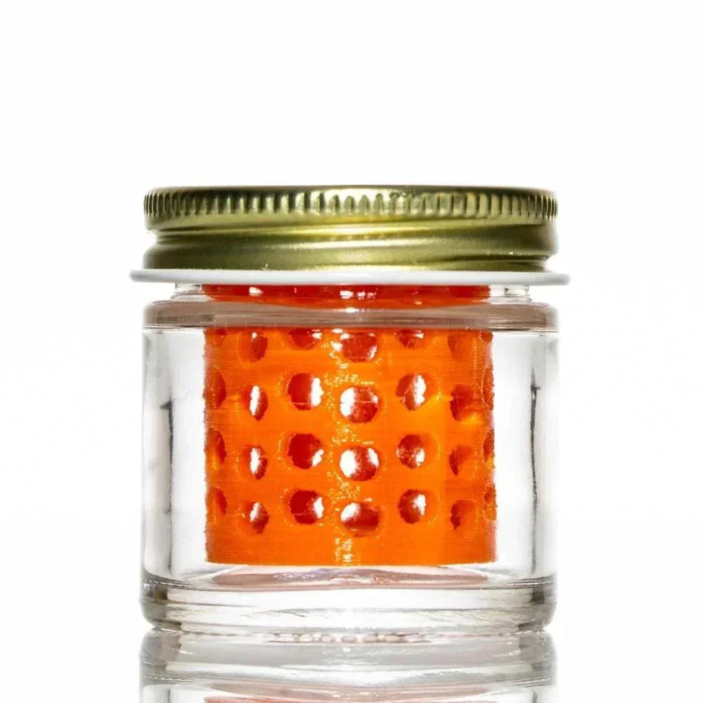 Clear glass jar with gold lid and orange perforated insert for cleaning glass accessories