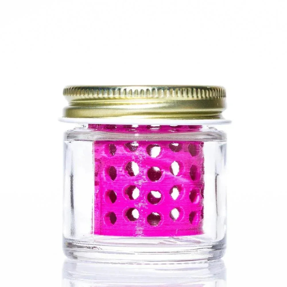 Clear glass jar with gold lid containing a pink perforated insert, on white background