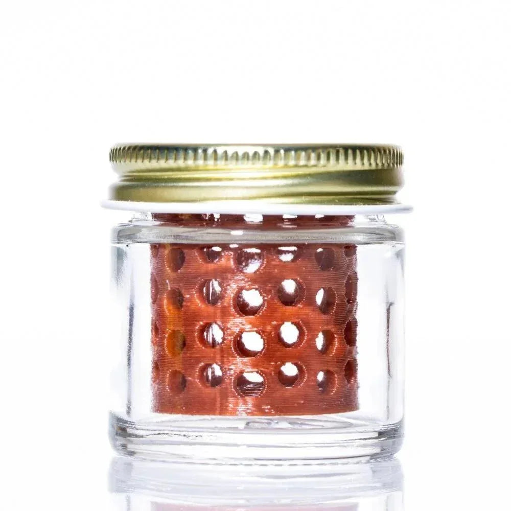 Small glass jar with metal lid and perforated brown insert, used for cleaning smoking accessories
