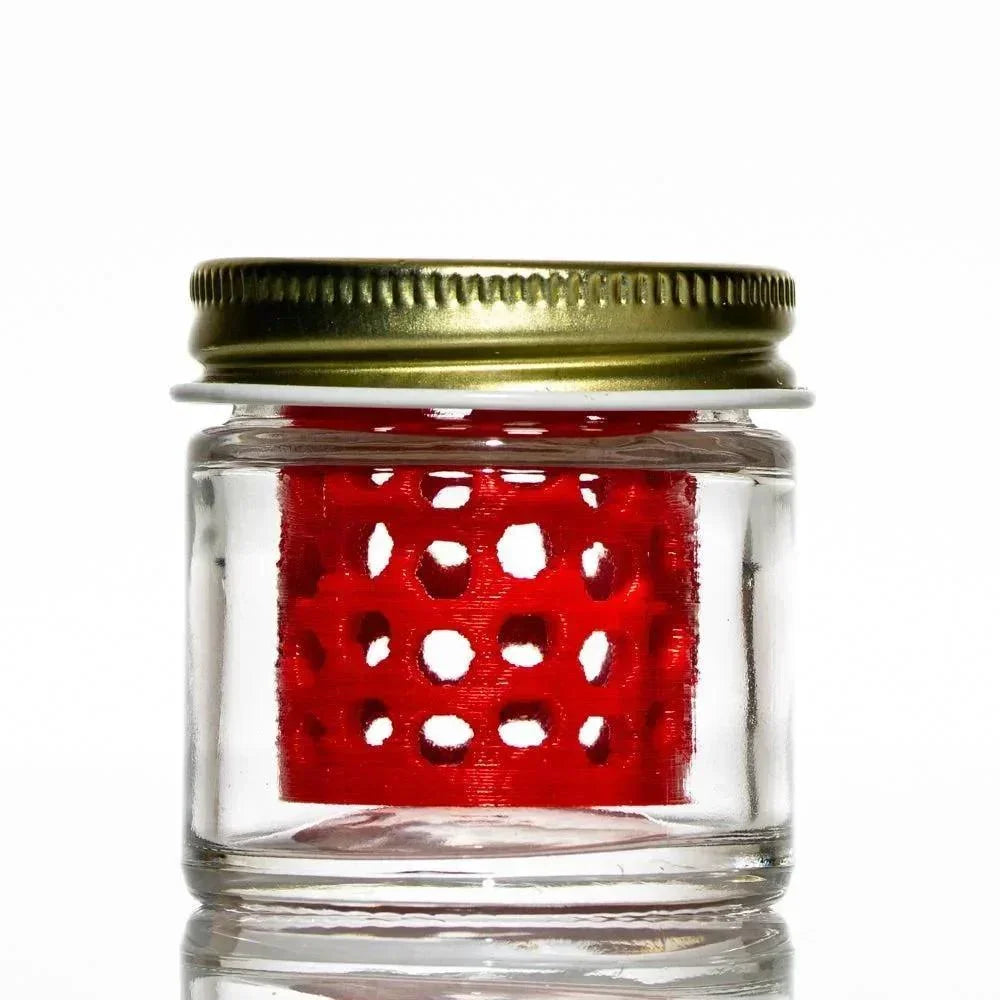 Small glass jar with gold lid and red honeycomb insert, used for cleaning glass pieces.