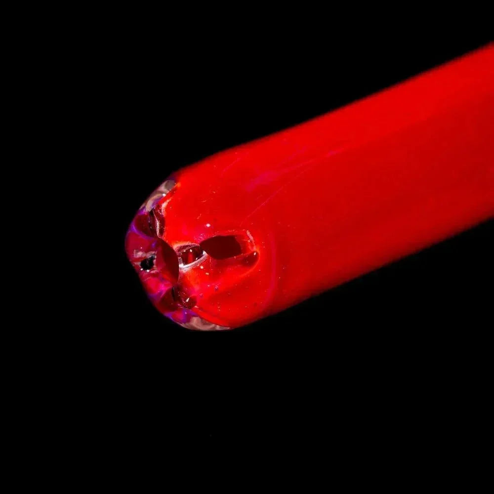 Close-up of vibrant pink glass pipe with intricate dragon eye design on a black background