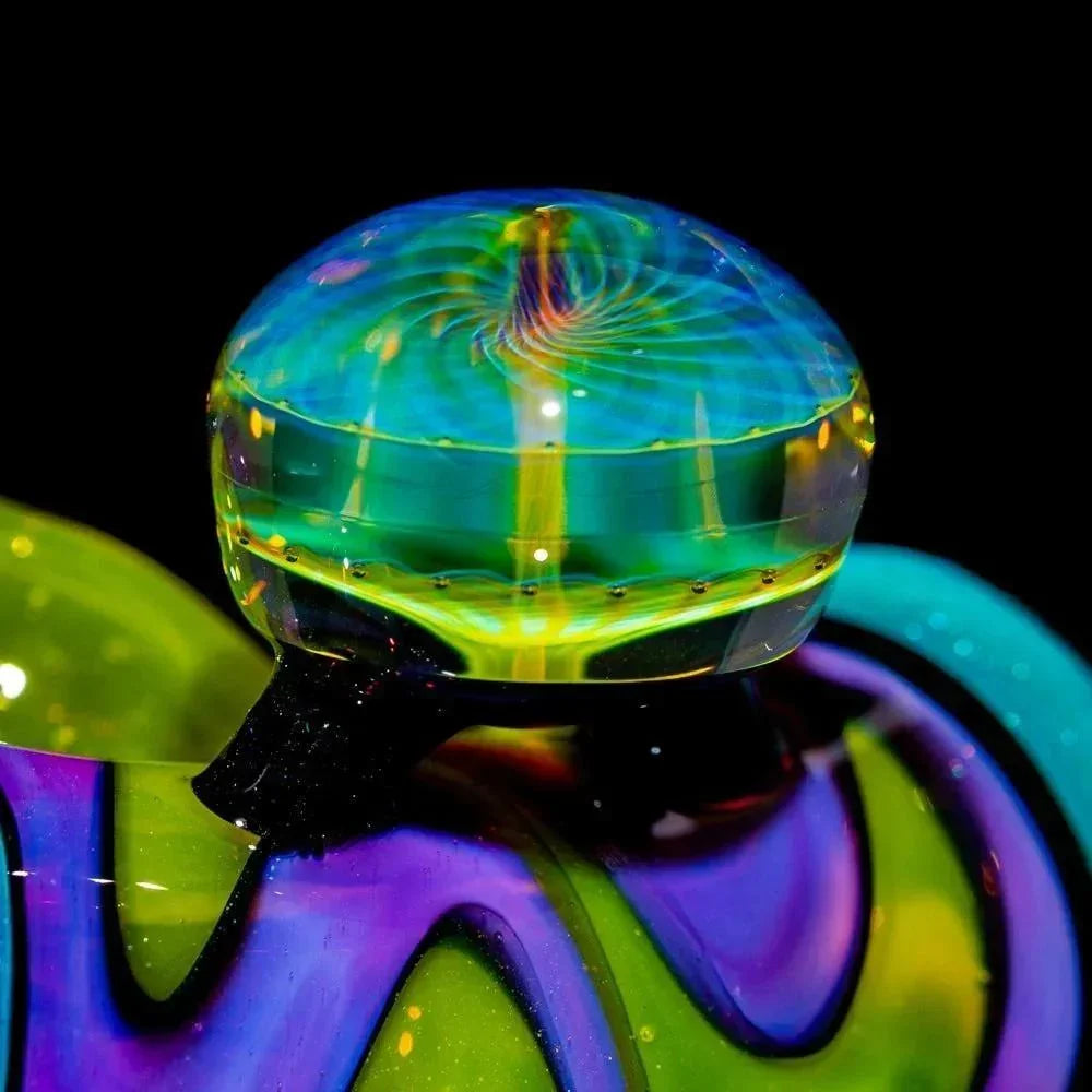 Close-up of a colorful heady glass art piece with swirling blue, green, and yellow patterns.