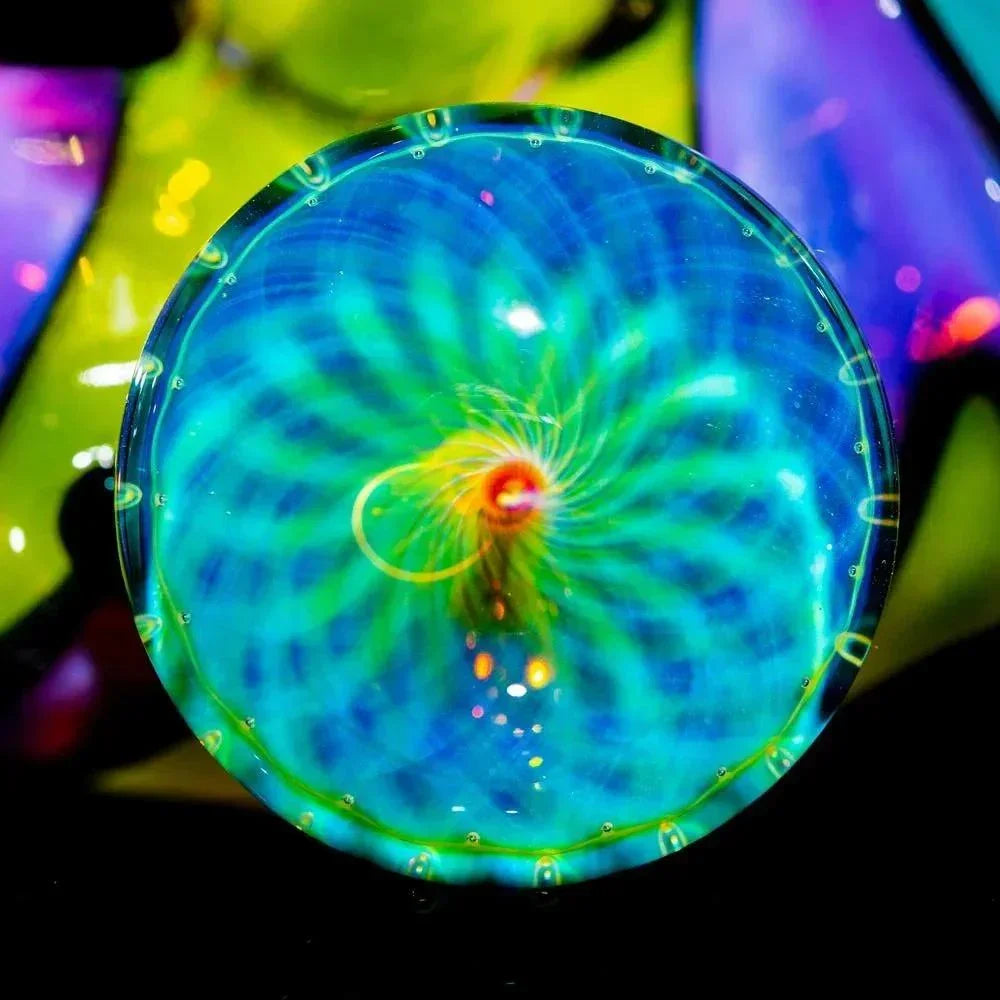 Close-up of a vibrant, handcrafted glass marble with blue and green swirling patterns