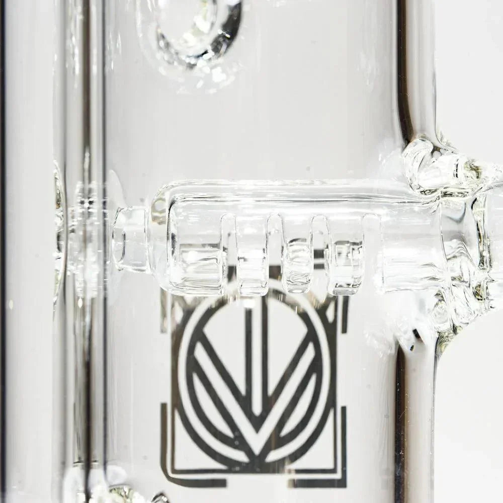 Close-up of clear glass water pipe with intricate percolator and engraved geometric design