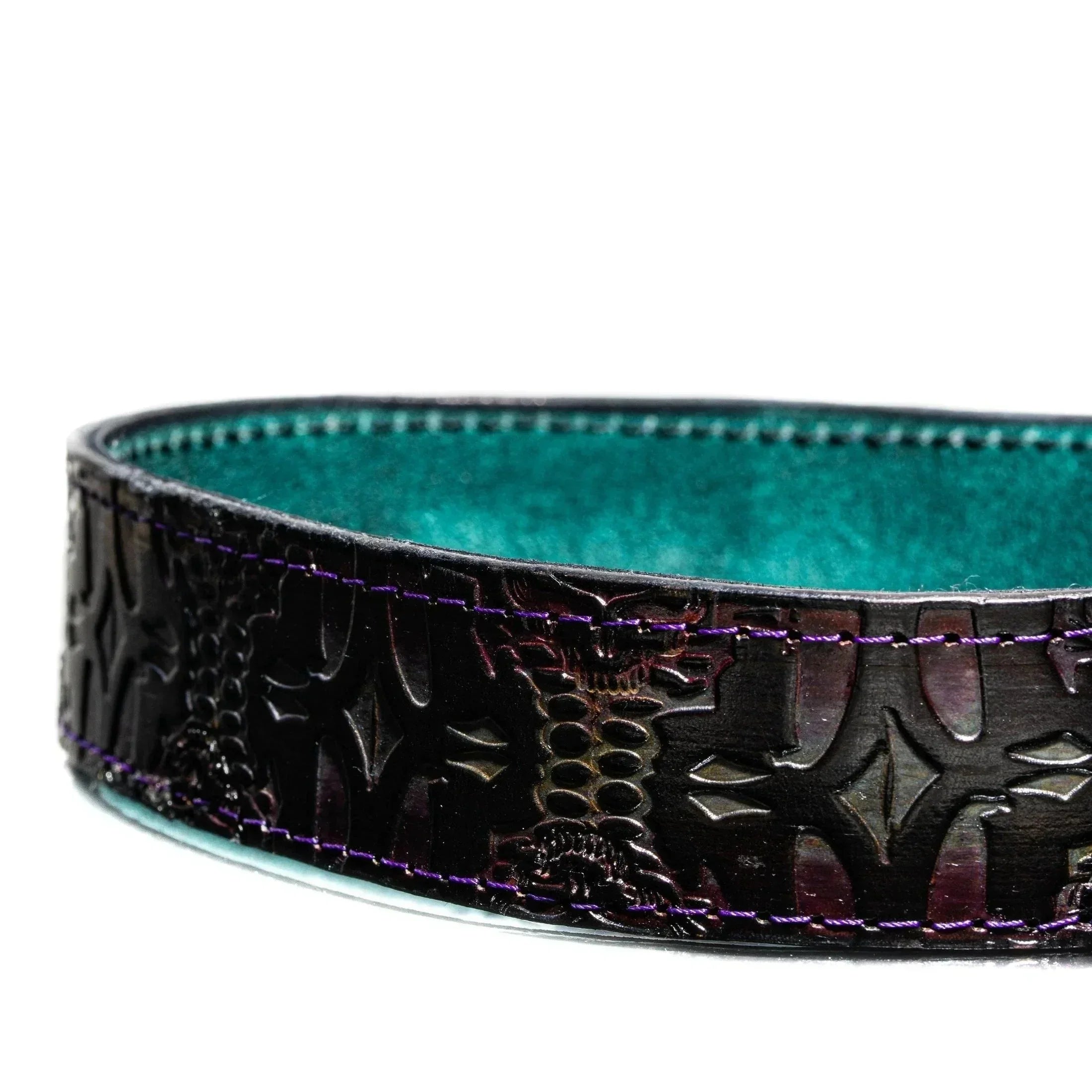 Close-up of a black tooled leather bag with teal interior and purple stitching detail