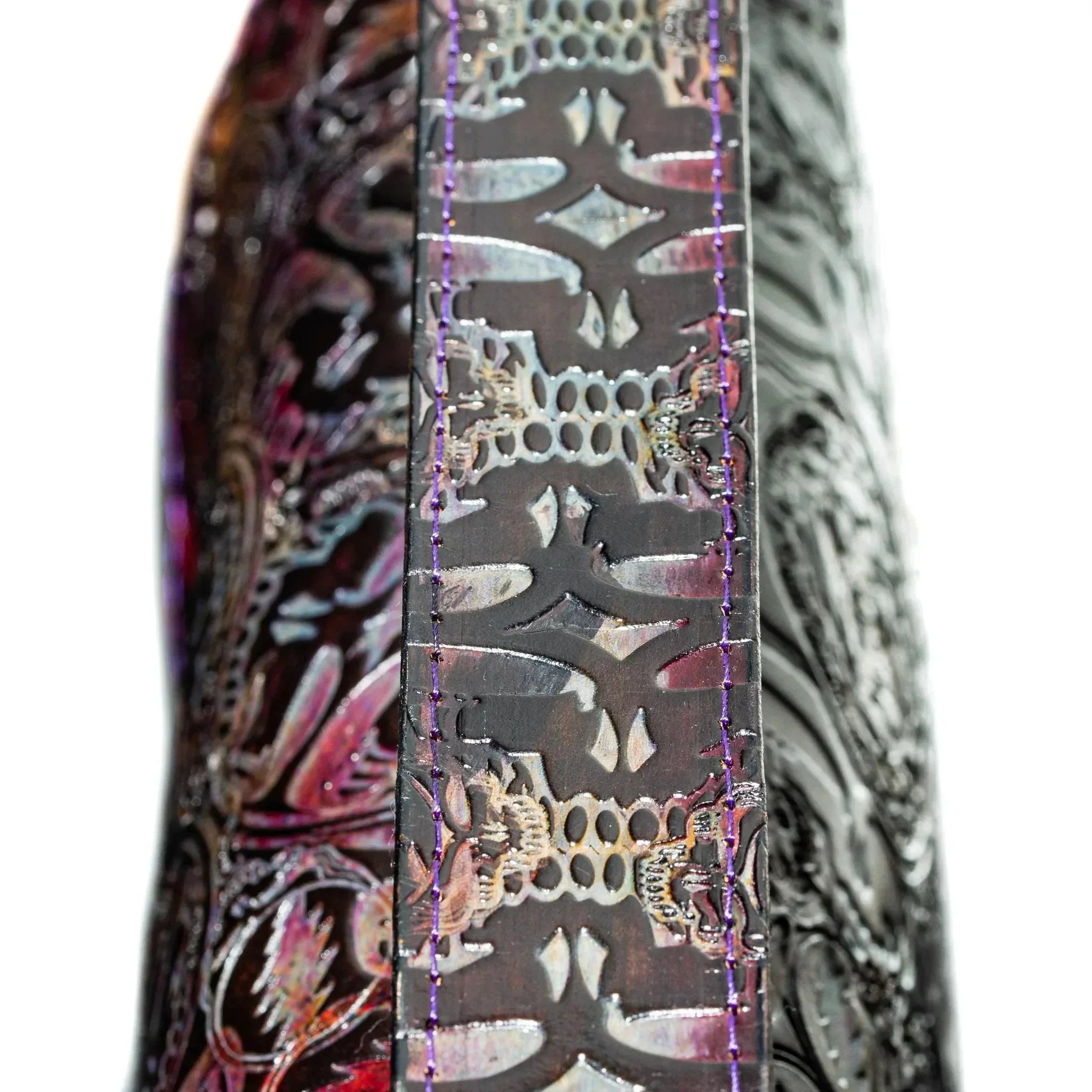 Close-up of embossed leather bag strap with intricate pattern and purple stitching