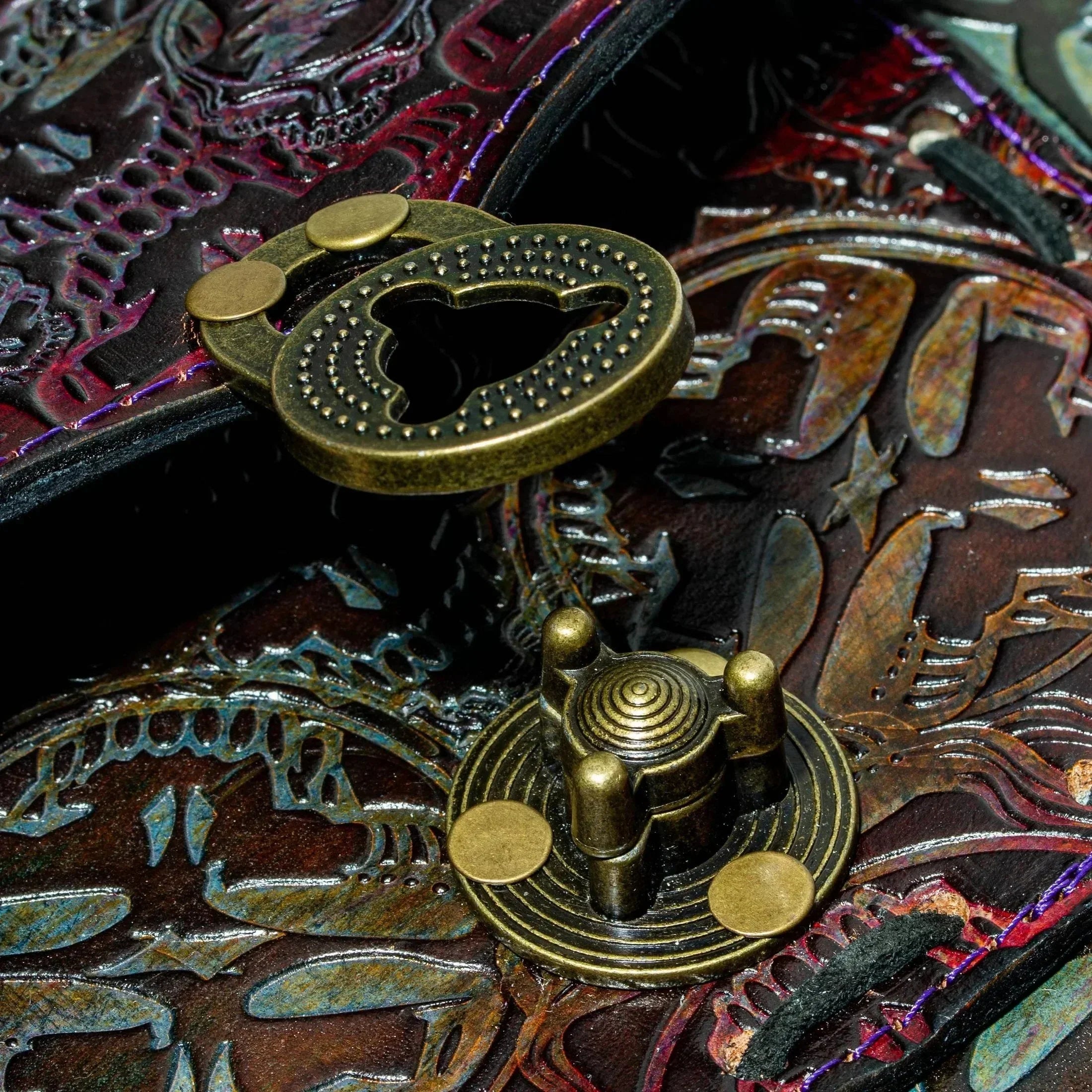 Close-up of ornate brass clasp on embossed leather side bag with intricate patterns
