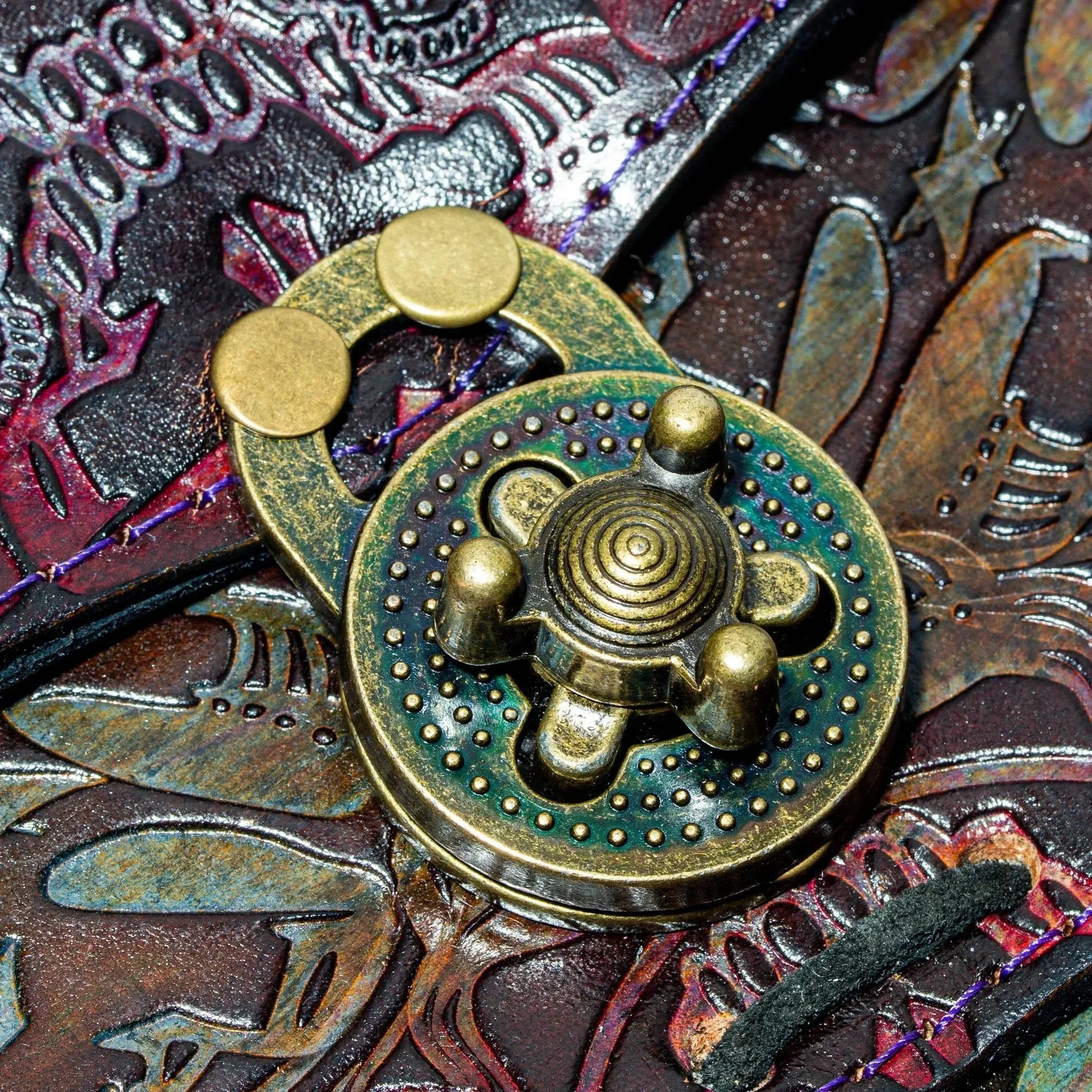 Close-up of embossed leather side bag with ornate brass clasp and colorful detailing
