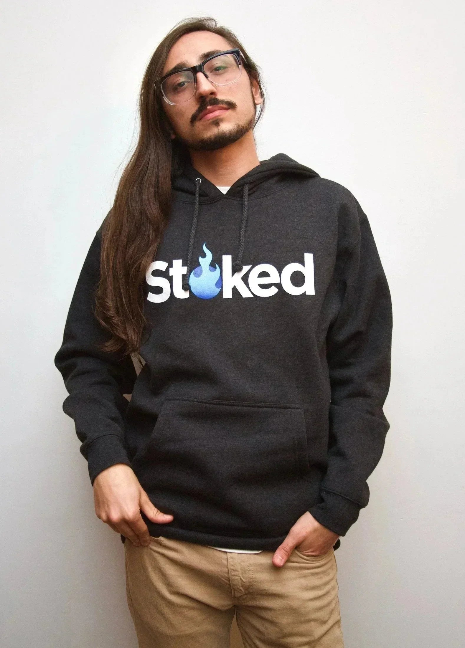 Man wearing black hoodie with blue flame 'Stoked' logo, casual streetwear style