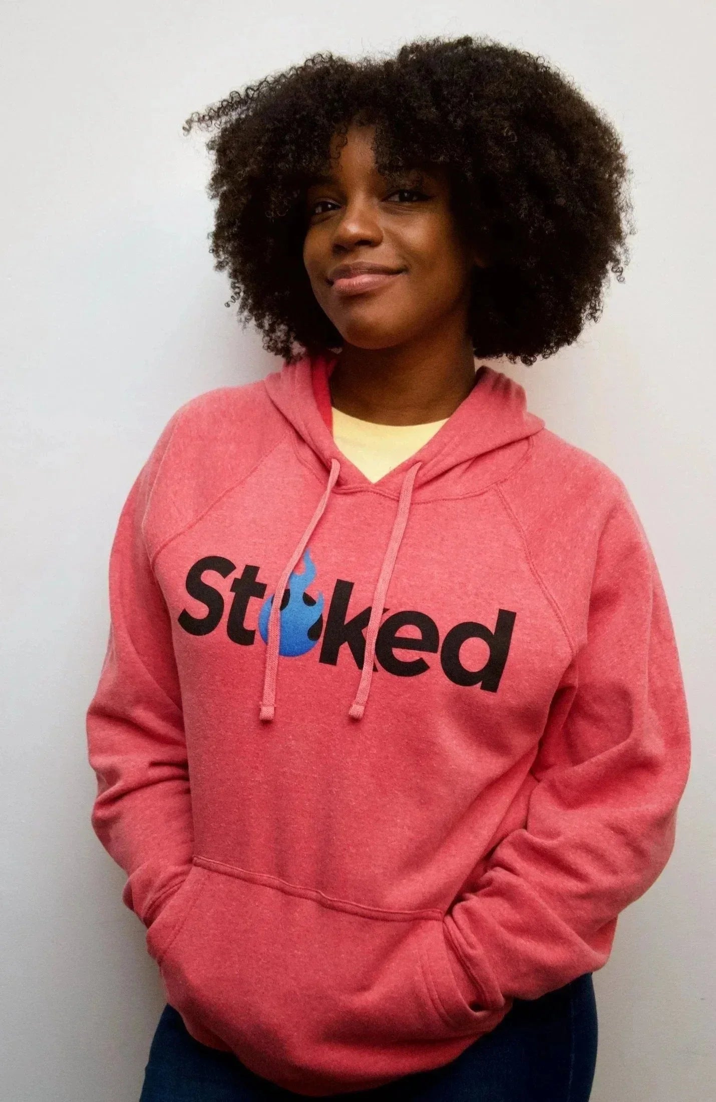 Person wearing a pink hoodie with Stoked logo and blue flame graphic