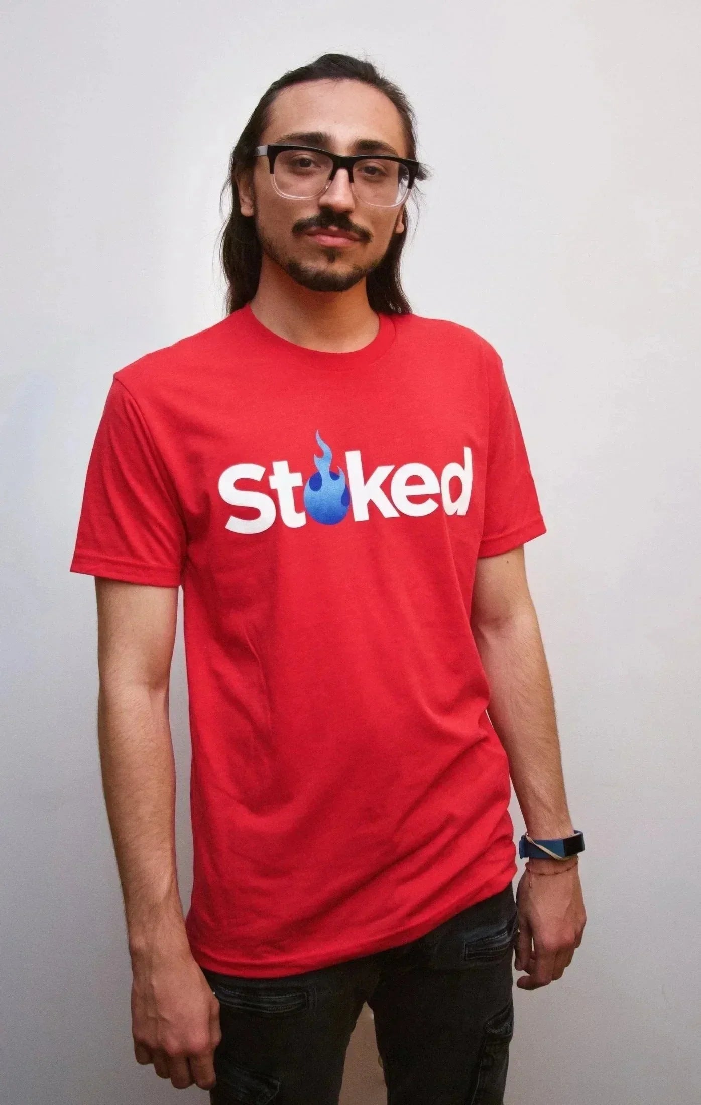 Man wearing red Stoked t-shirt with blue flame graphic, casual streetwear style