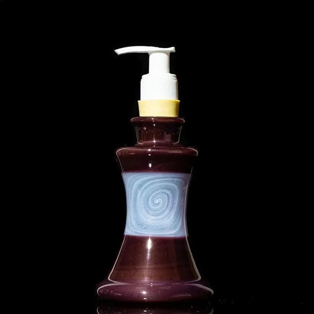 Purple glass soap dispenser with blue swirl design and pump top on black background