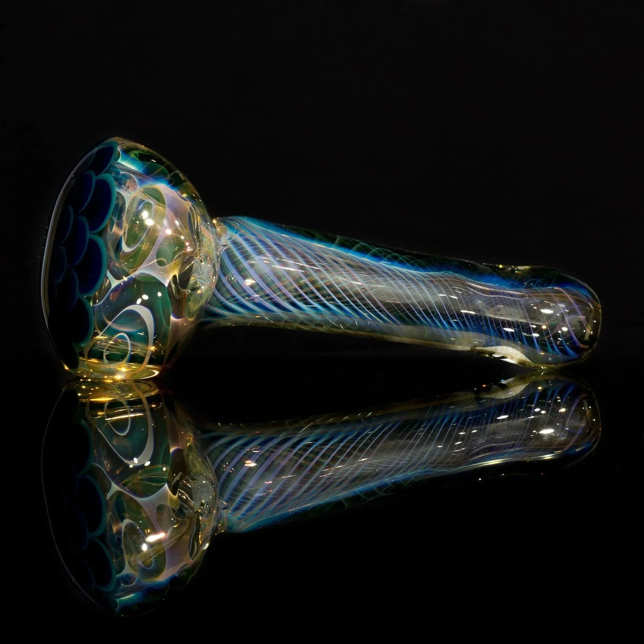 Iridescent heady glass pipe with blue swirls and scale patterns, displayed on reflective black surface