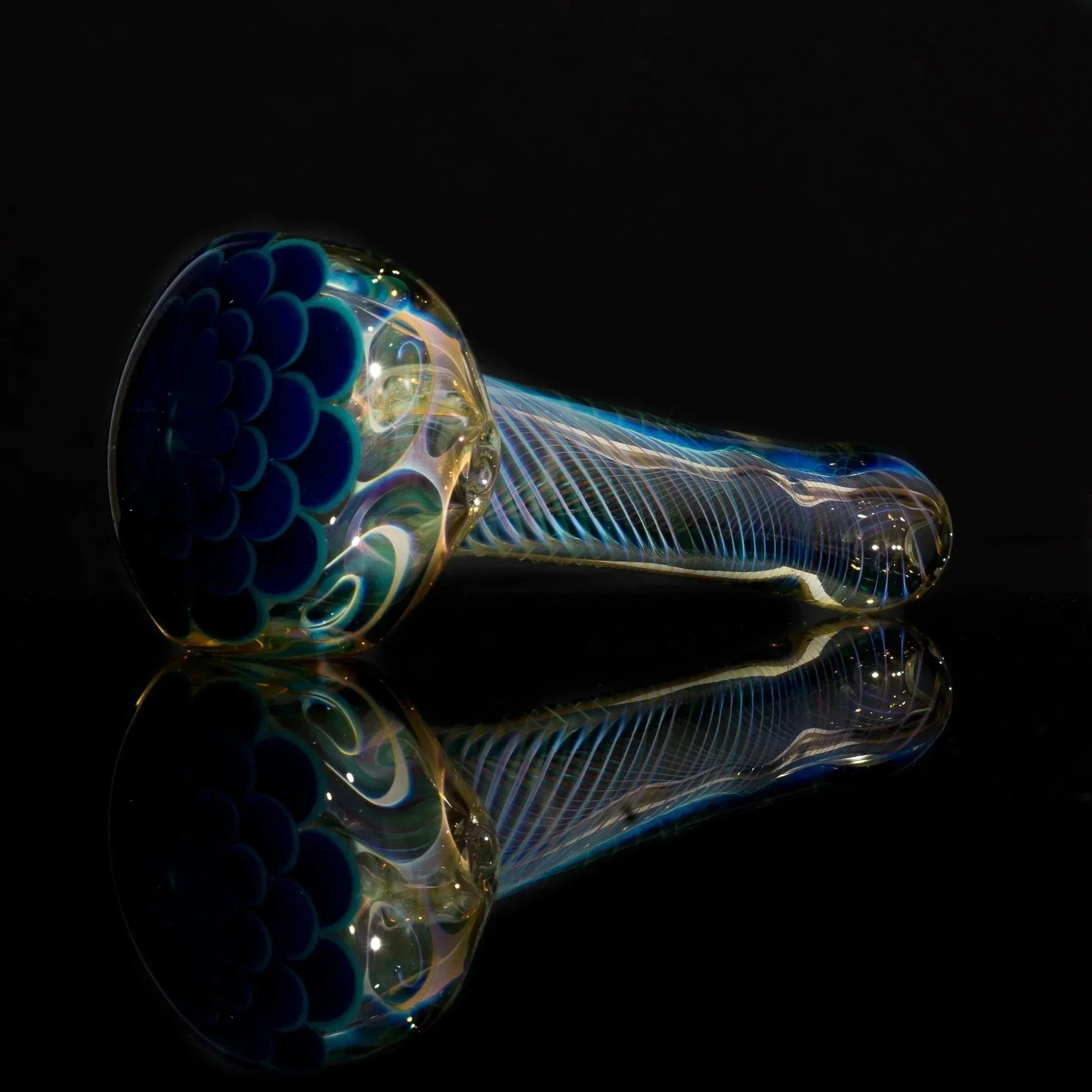 Handblown glass pipe with blue scale design and iridescent swirls, reflective surface