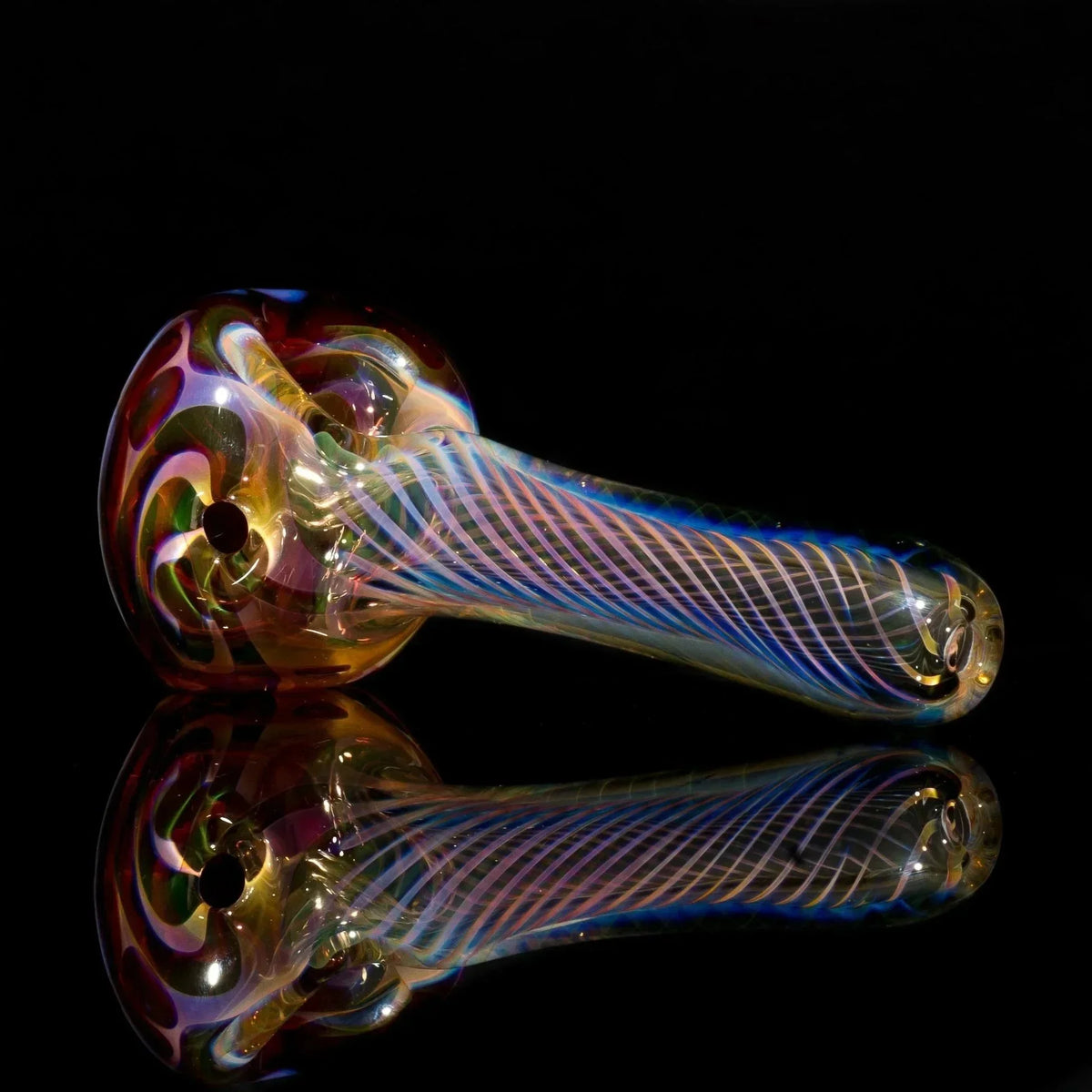 Iridescent glass pipe with swirling colors and striped stem, reflecting on black surface