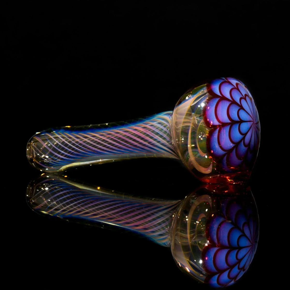 Colorful heady glass pipe with swirls and floral design on black reflective surface