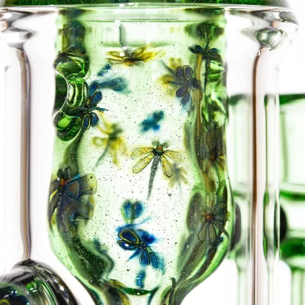 Close-up of green glass water pipe with detailed dragonfly and floral artwork