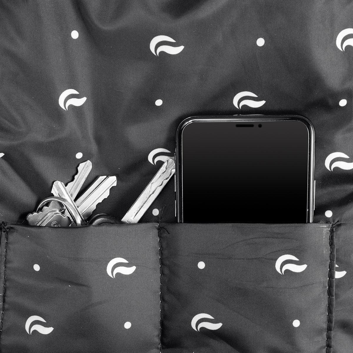 Close-up of inside backpack pockets holding keys and a smartphone, black patterned lining.