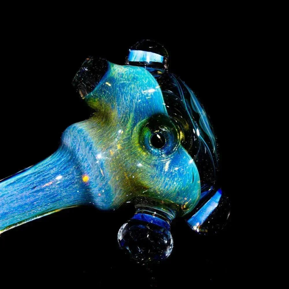 Faceted glass smoking spoon with blue and yellow swirls on a black background