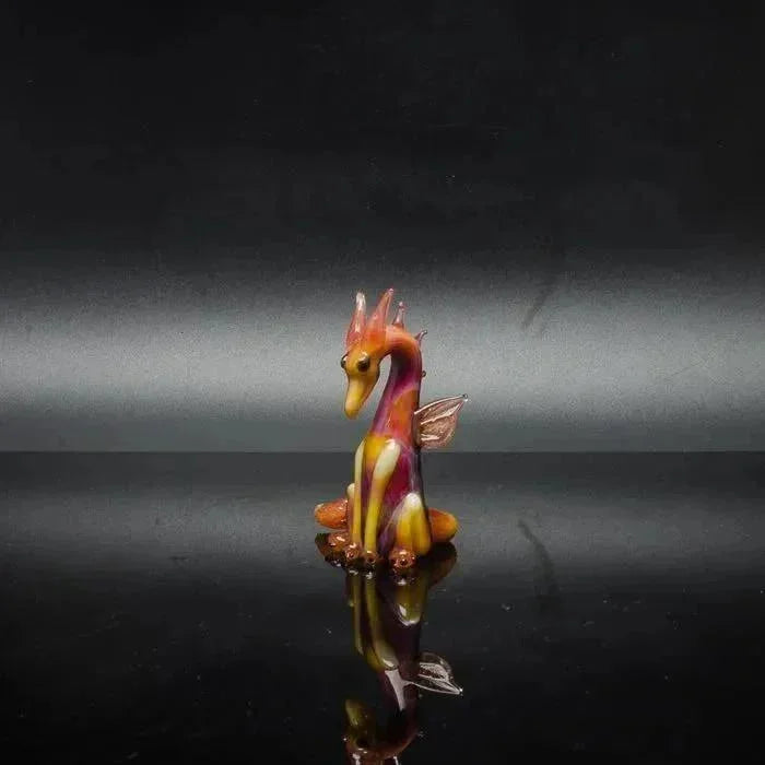 Colorful glass dragon figurine with vibrant orange and purple hues, reflecting on glossy surface