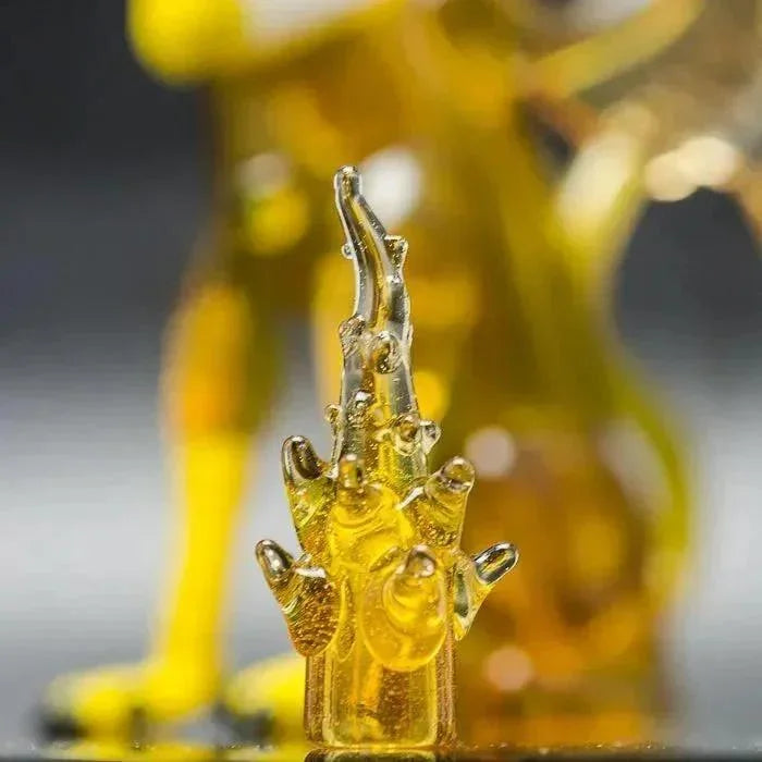 Golden glass hand sculpture with intricate details, showcasing heady glass artistry.