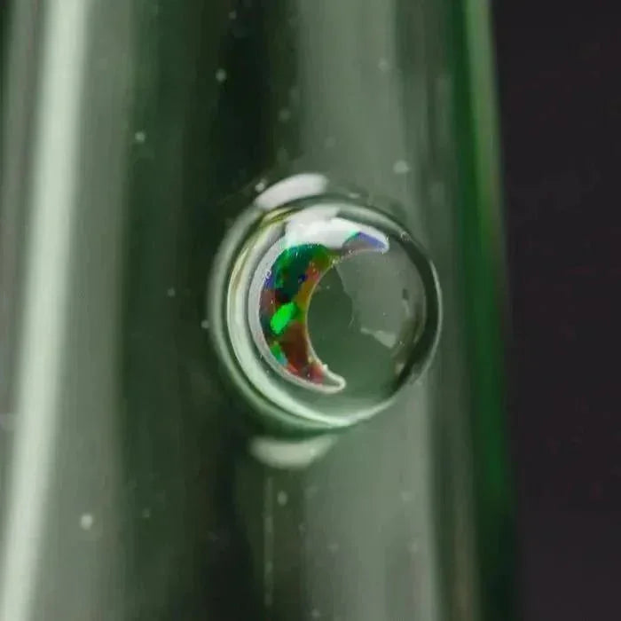 Close-up of a glass pipe with a colorful, iridescent crescent moon design embedded in clear glass.