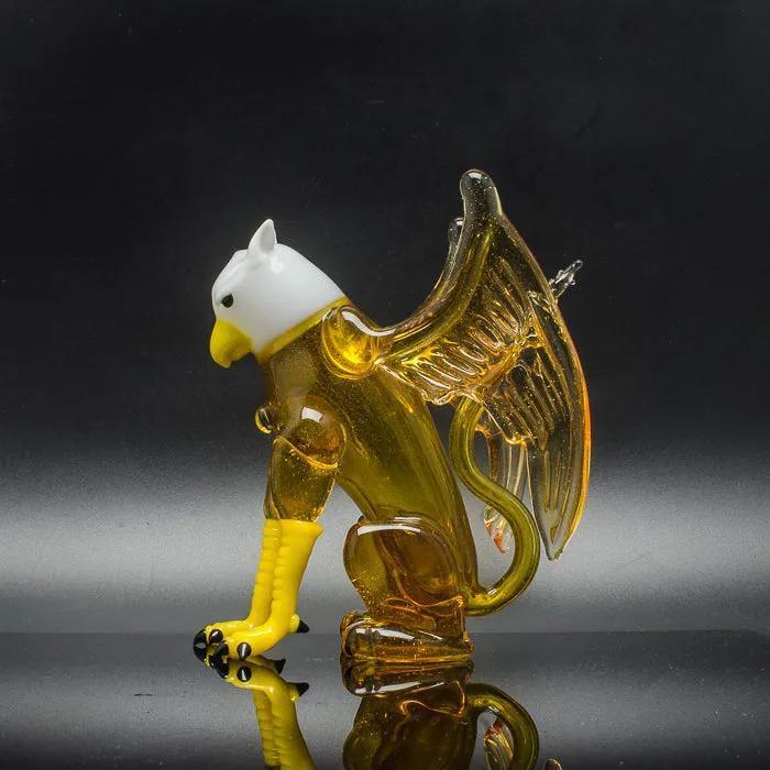 Amber glass eagle sculpture with white head and yellow beak, showcasing intricate wings and talons.