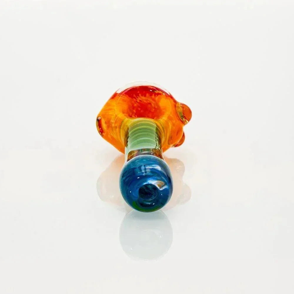Colorful glass spoon pipe with rainbow frit design and honeycomb pattern on white background.