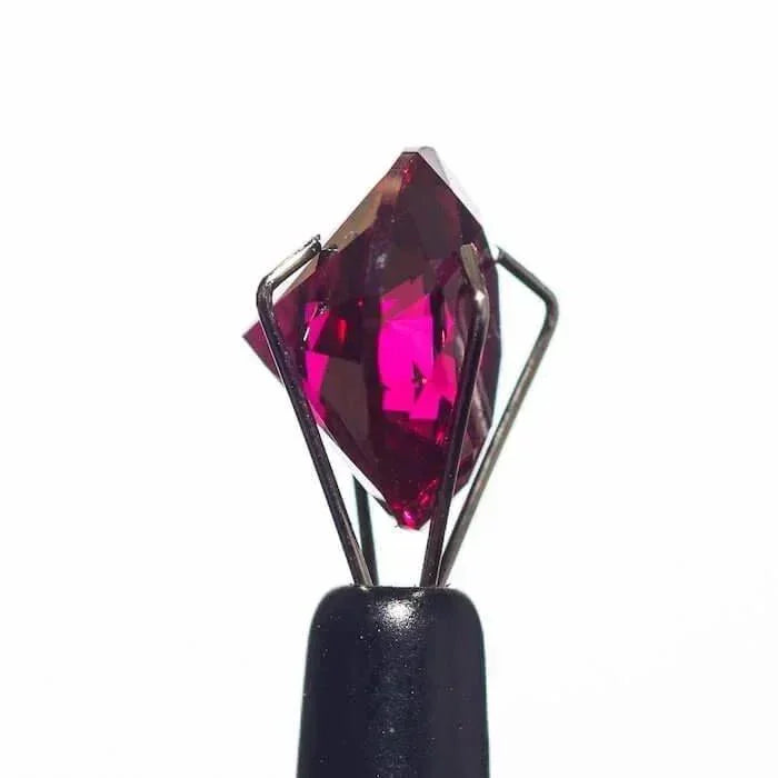Faceted pink gemstone in metal prongs on black handle, heady glass accessory