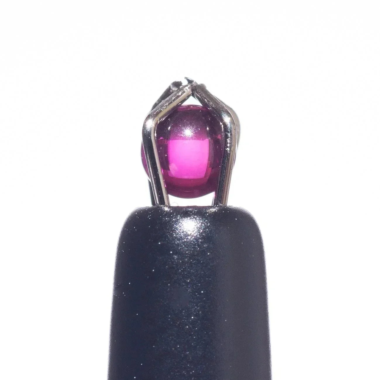 Vibrant pink glass carb cap with metallic prongs on black base, ideal for dab rigs and vaporizers