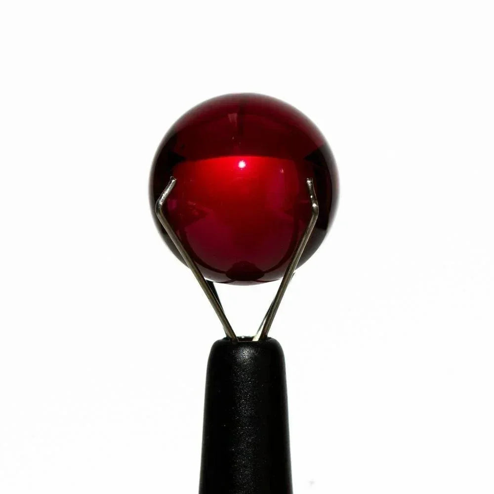 12mm ruby glass terp pearl held by metal tongs on a white background
