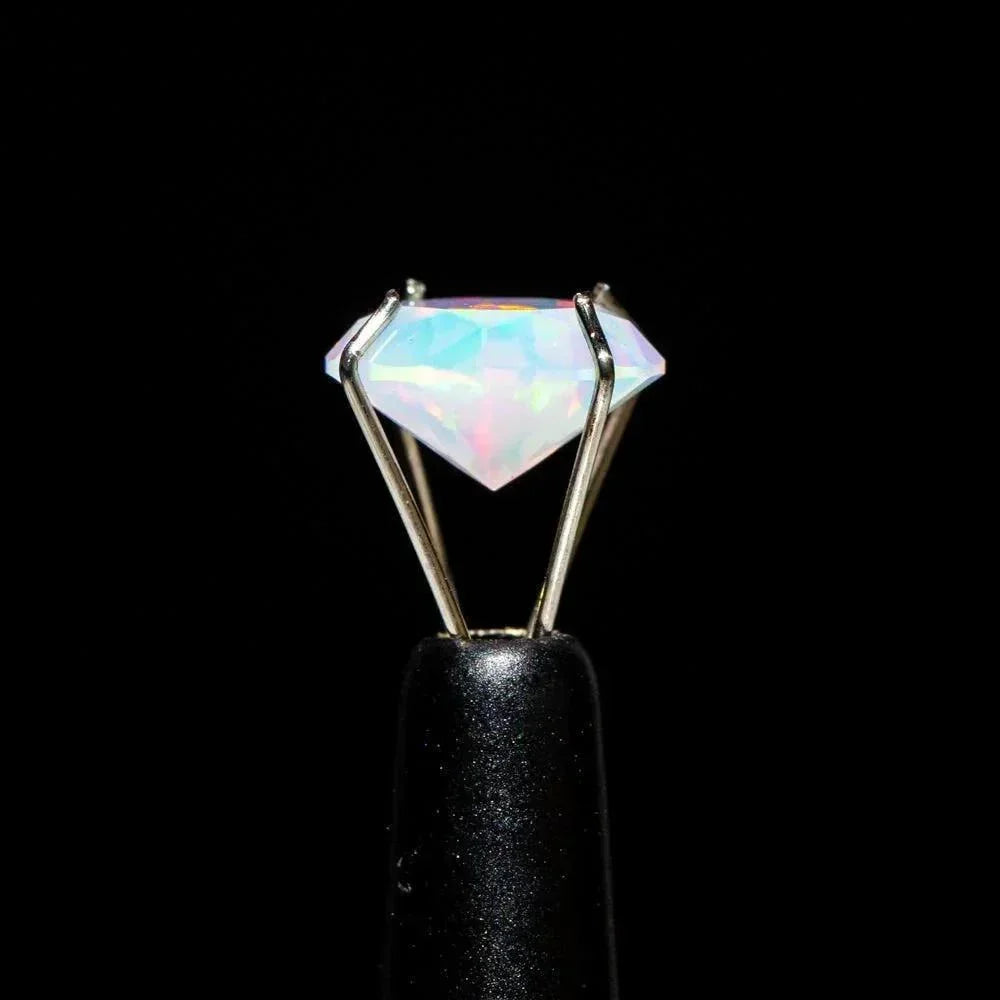 8mm diamond-cut opal gemstone held by metal prongs on black background