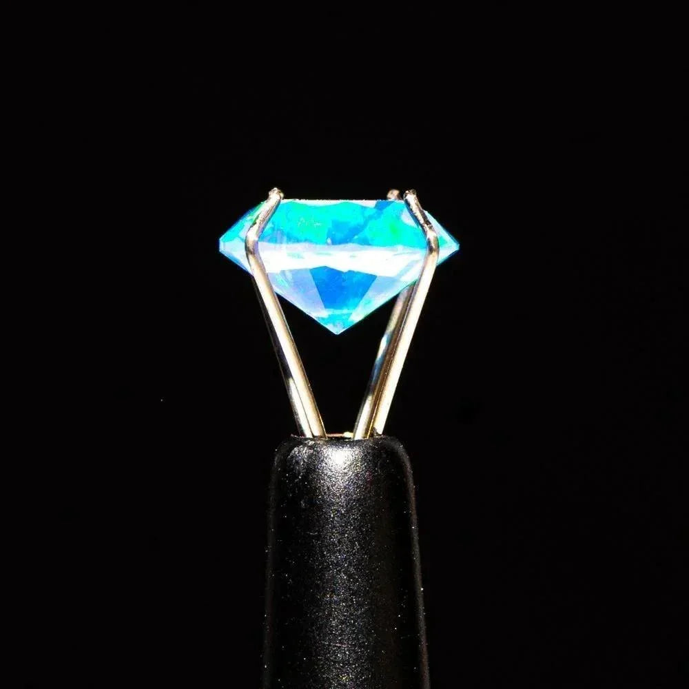 8mm diamond-cut opal terp pearl with blue hues held by metal tweezers on black background