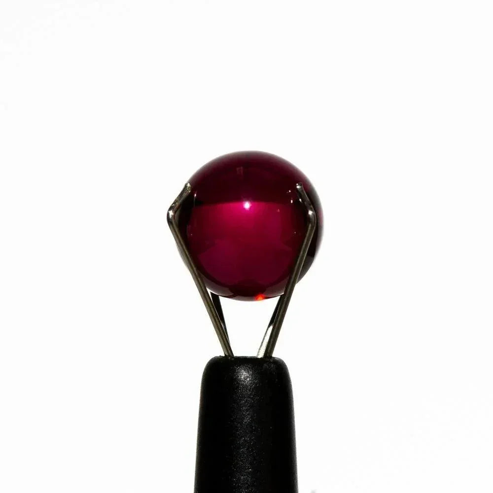 8mm ruby terp pearl for dab rigs and vaporizers, held by a tool on white background