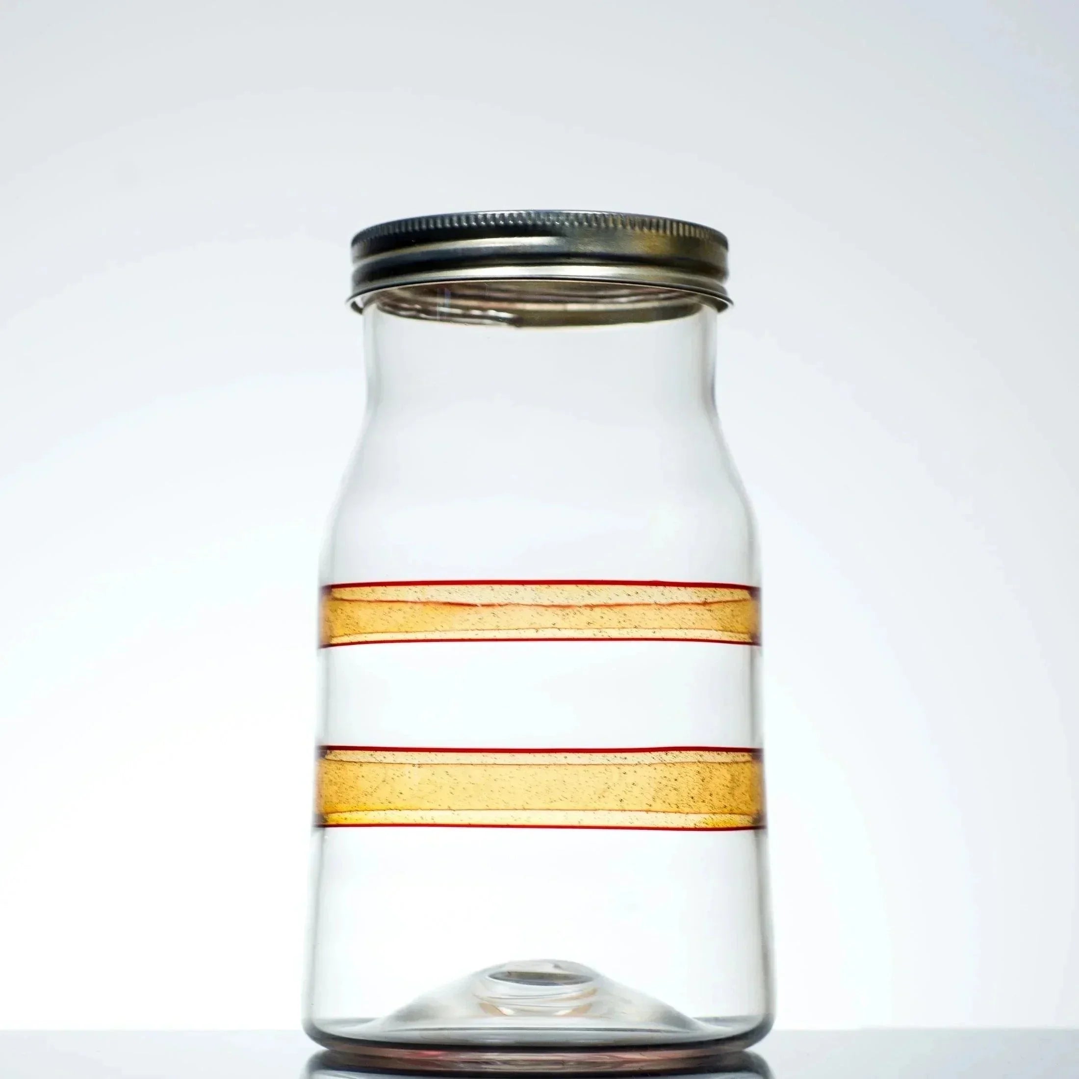 Clear glass jar with amber stripes and metal lid, ideal for storage or display.
