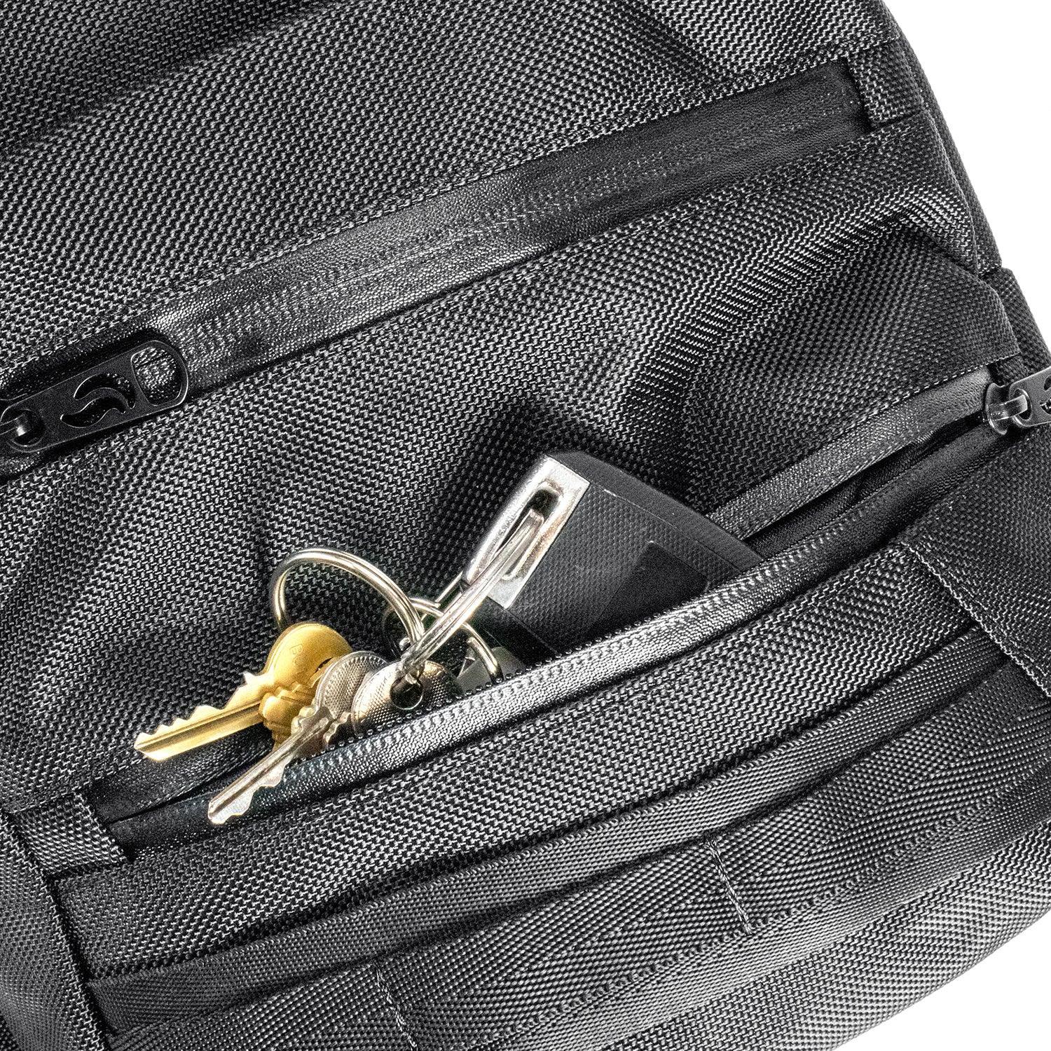 Closeup of keys and a key fob in the front zippered pocket of a black textured backpack