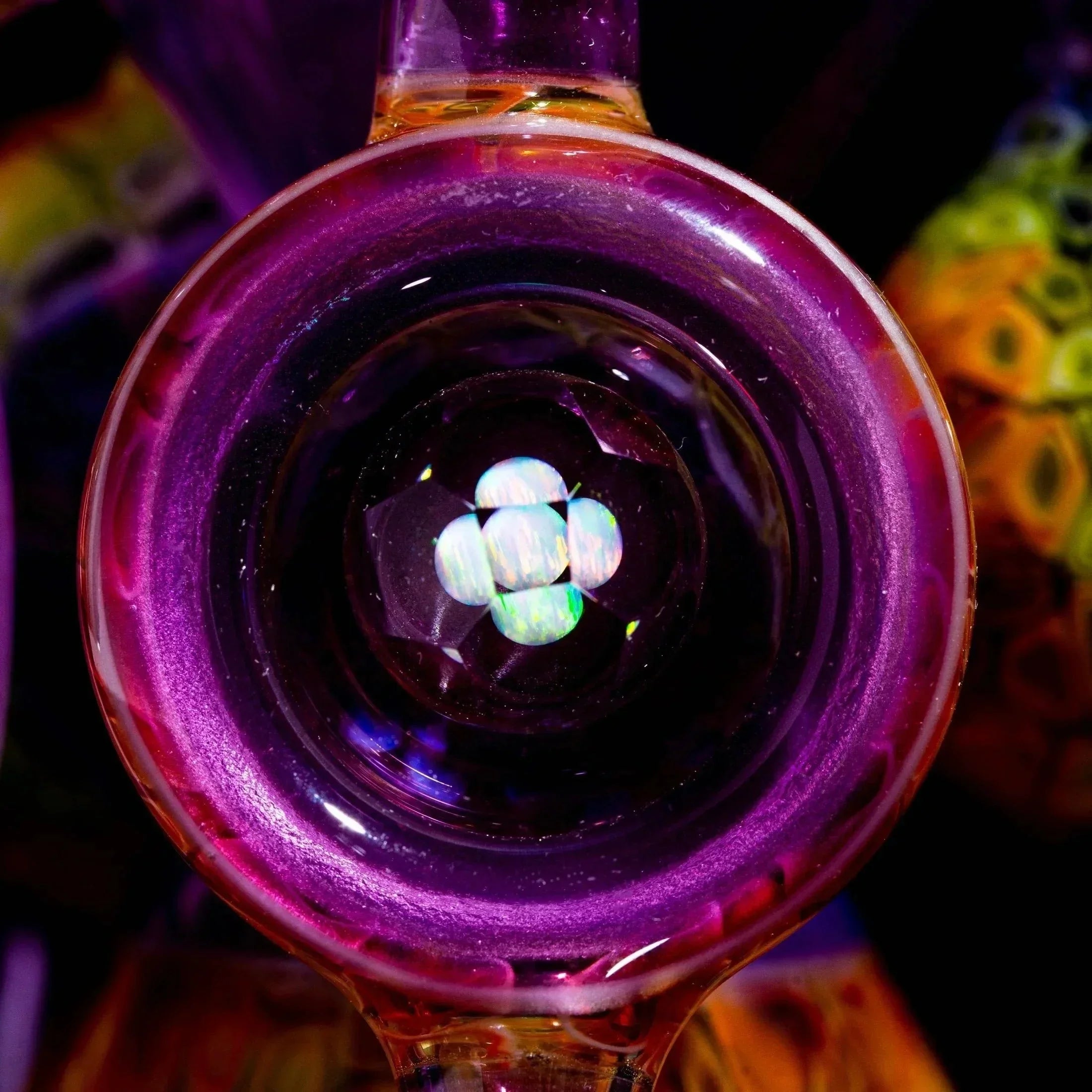 Close-up of a colorful glass art pipe with vibrant purple hues and opal accent marble.