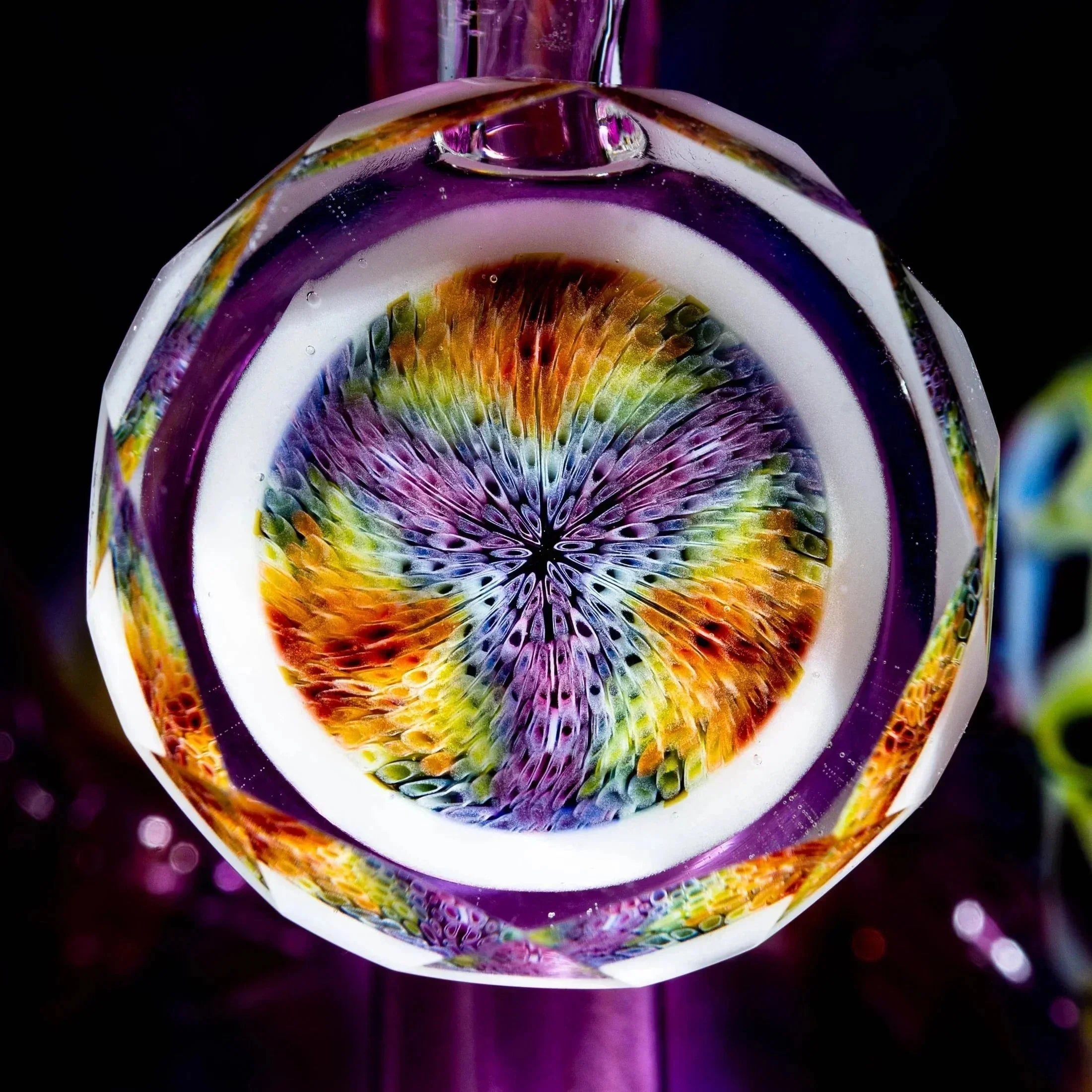 Colorful heady glass art with intricate rainbow pattern and faceted edge, close-up view