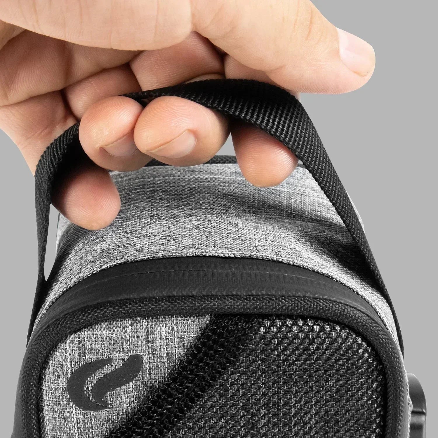 Close-up of hand holding gray carrying case with black zipper and mesh pocket