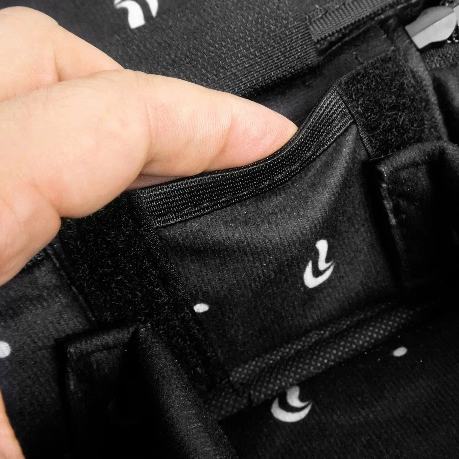 Close-up of hand opening a black accessory bag with inside pocket and soft lining